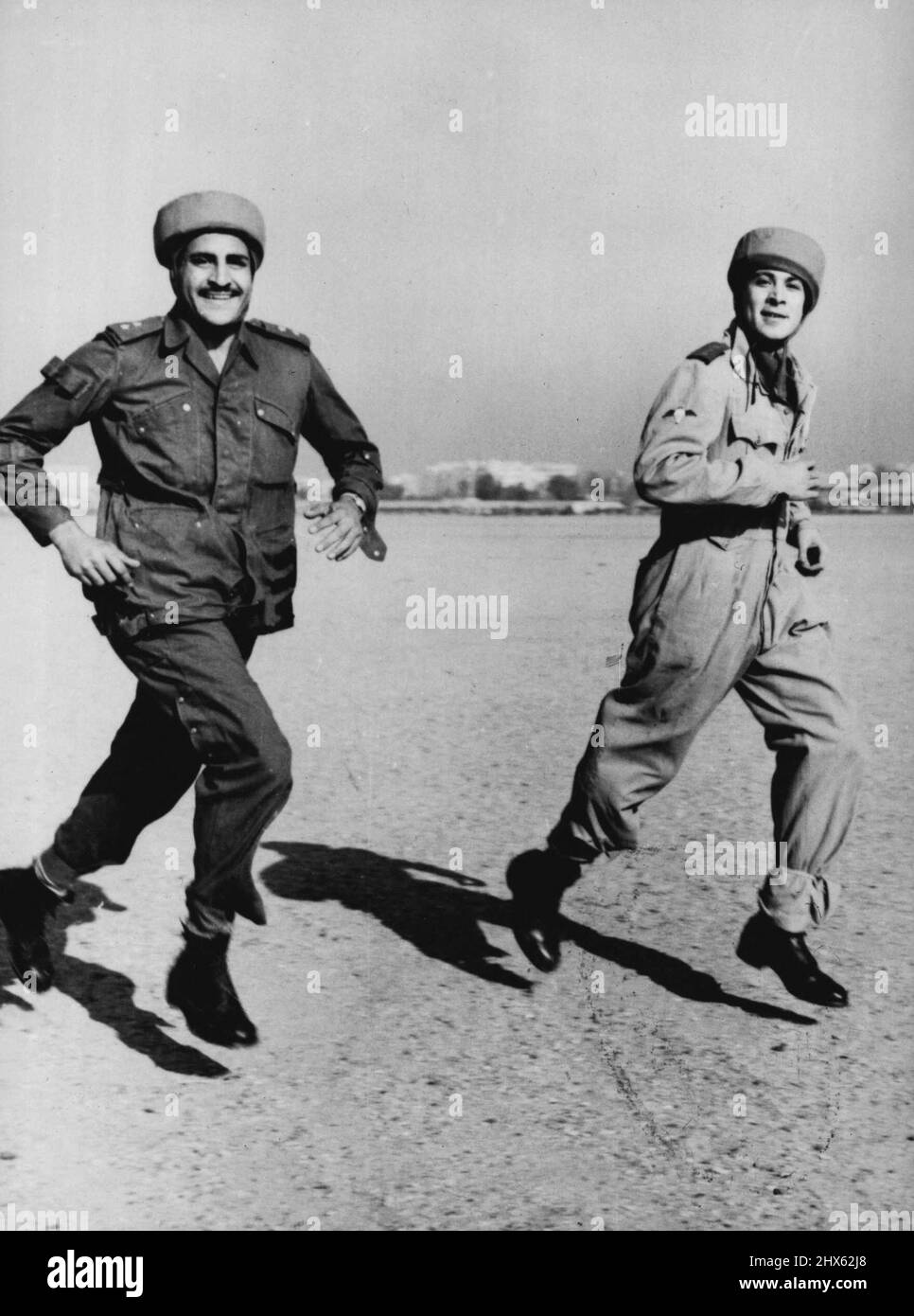 Egyptian Paratroopers Stage First Mandeuvers Captain Steimel (right, first name not available), German Instructor, runs to the waiting aircraft with an Egyptian paratrooper, during the first manoeuvres of the newly created Egyptian paratroop unit, November 29th. A Dakota aircraft of the Egyptian Royal Air Force took off from the Almaza Military Airport, with four Egyptian parachutists during the manoeuvres and later the parachutists baled out over a field. German experts who for several months h Stock Photo