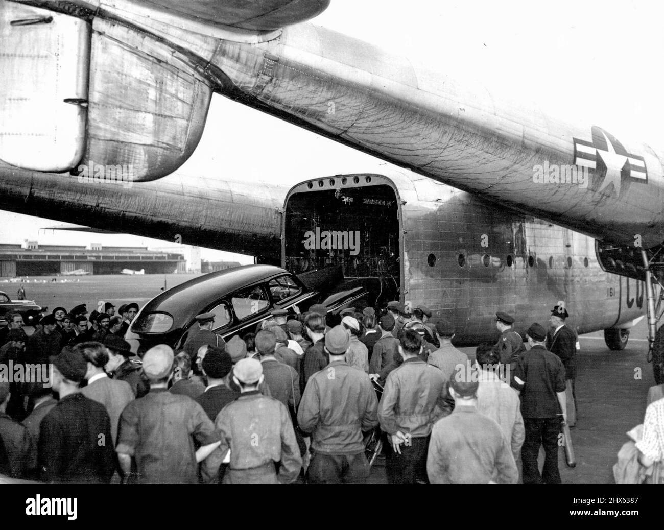 'Flying Boxcar' Takes Cars From Berlin. An American car from Blookaded Berlin is loaded into a United States Air Force 'Flying Boxcar' (C-81) at Tempelhof Airport, September 14. The aircraft is the first of its kind to be introduced on the Berlin 'Air-Life' and the car is the first of many American-owned vehicles that are to be flown out of the German capital. September 16, 1948. (Photo by Associated Press Photo). Stock Photo