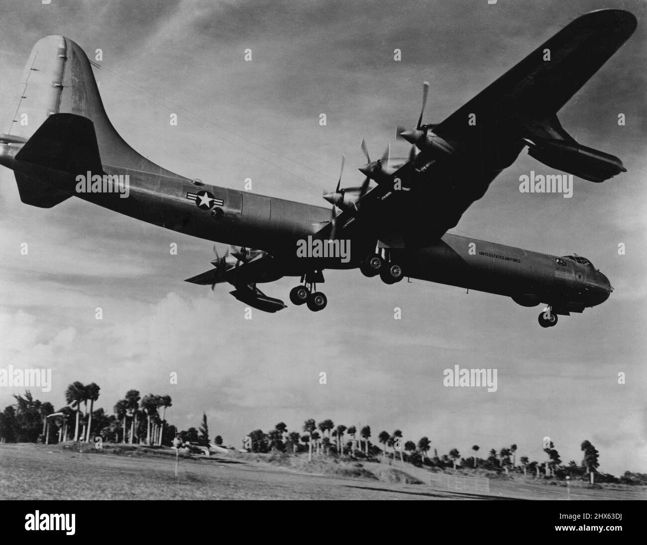 Supergiant of The Skies -- The World's first international bombers a 10 engine Convair B-36 - puts its two, huge, 4-wheel landing gears down for a landing at a tropical Air Force base. This supergiant of the skies has a wingspread of 230 feet-almost as long as a football field. Its length is 162 feet, and its height at the tail is nearly 47 feet or 5 stories high. With four J-47 jet engines nestled ***** its Six 3,500 horsepower reciprocating engines. This mighty Air Force bomber is capable of c Stock Photo