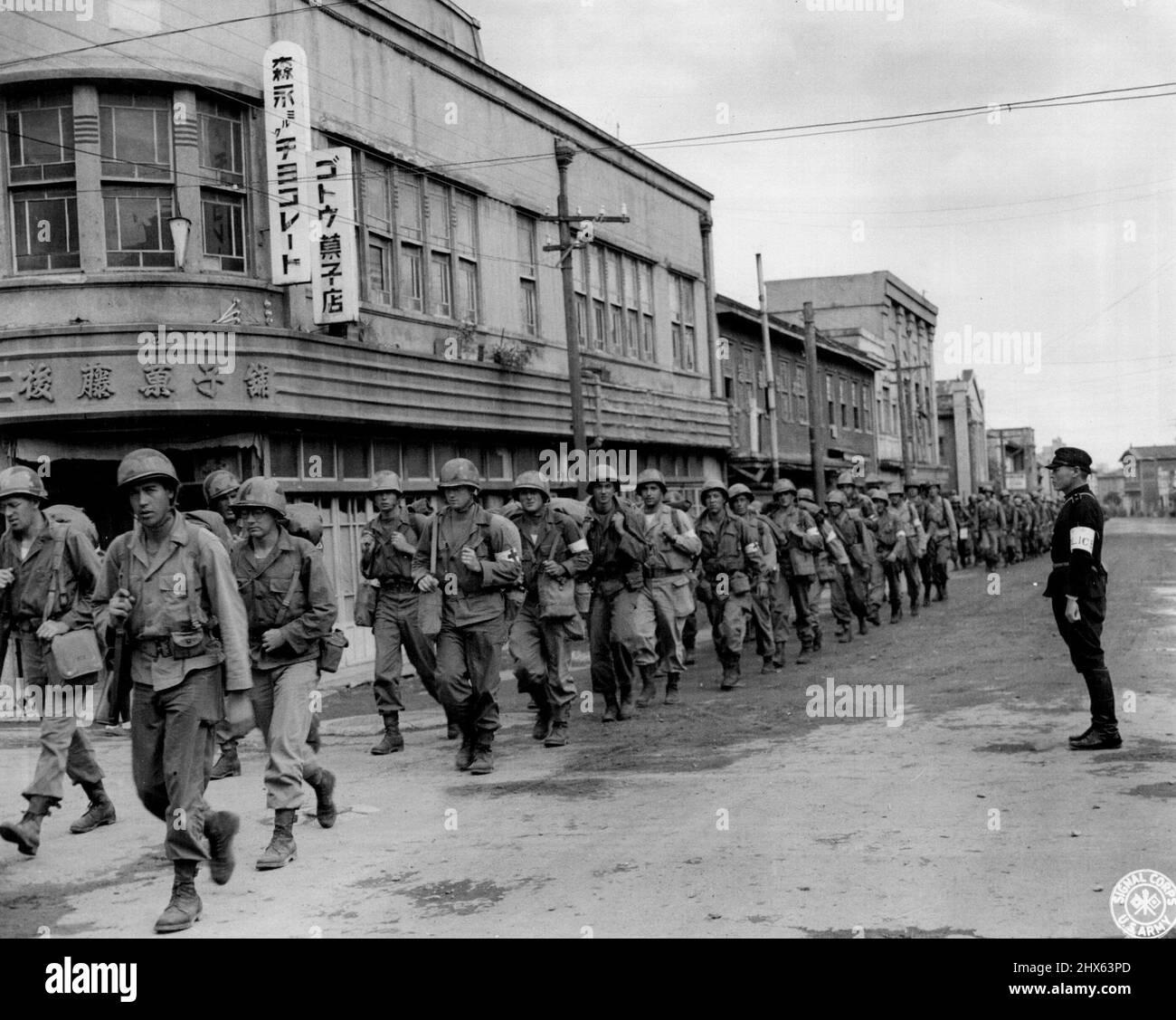 Occupation troops, of the 81st Infantry Division, march into Hirosaki, nead Aomori, Japan, with a Japanese policeman to guide them into the city. Scenes such as this, are typical as the American Forces' take up their zones of occupation. February 25, 1946. (Photo by US Signal Corps Photo). Stock Photo