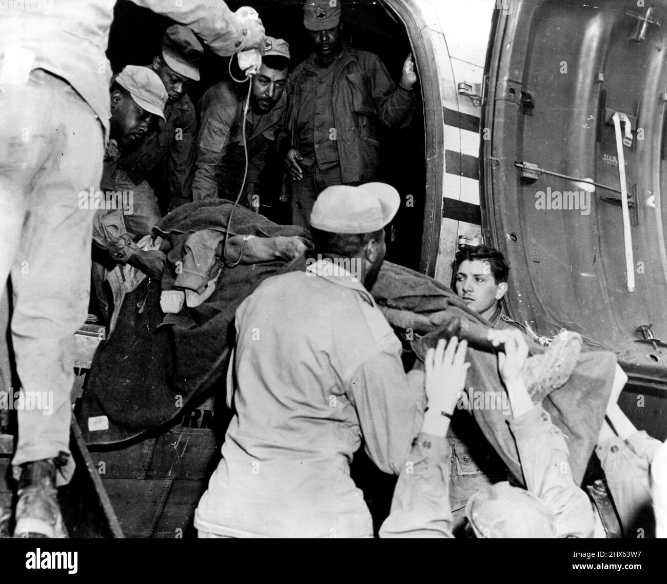 United States Soldier, wounded while fighting with ***** forces in Korea, is lifted into a transport airplane at a front-line airstrip in North Korea, to be evacuated to Japan. A medical corpsman (extreme left) administers life-saving blood plasma. Within several hours this soldier was receiving expert medical attention and care at a modern, U.S. Army hospital in northern Japan. December 29, 1950. (Photo by United States Information Service). Stock Photo