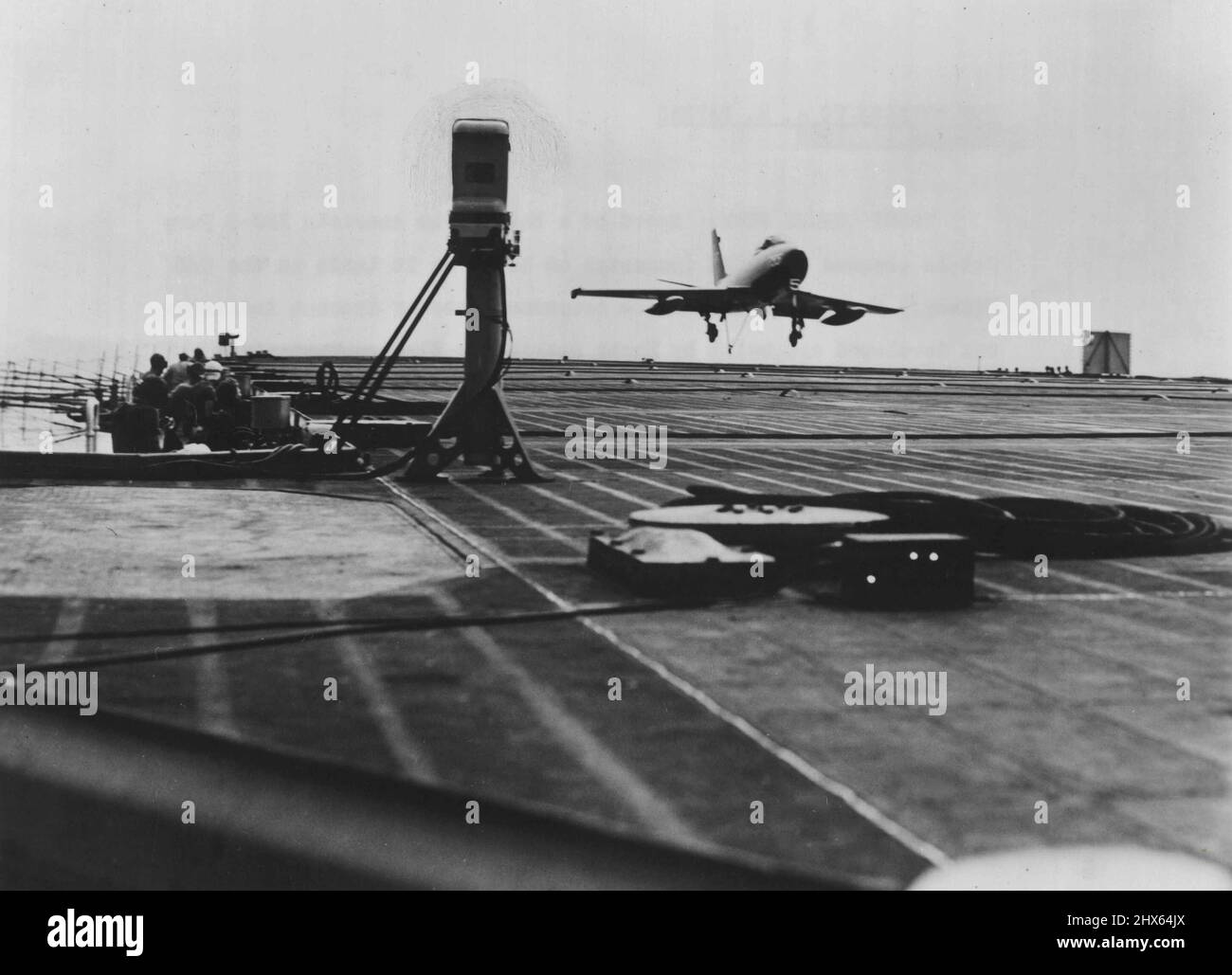 Trodi Checks Fury : Speed of a Navy North American XFJ-2 Fury Jet is checked by Trodi (padestal at left) as it lands on the USS Midway. The new instrument, a touchdown, rate of descent indicator, was developed and built by North American's Electro-Mechanical Department. It makes it possible to determine the proper rate of descent for carrier landing in a fraction of the time previously required. Trodi sends out two beams of light which the approaching plane intersects and the instrument then rec Stock Photo