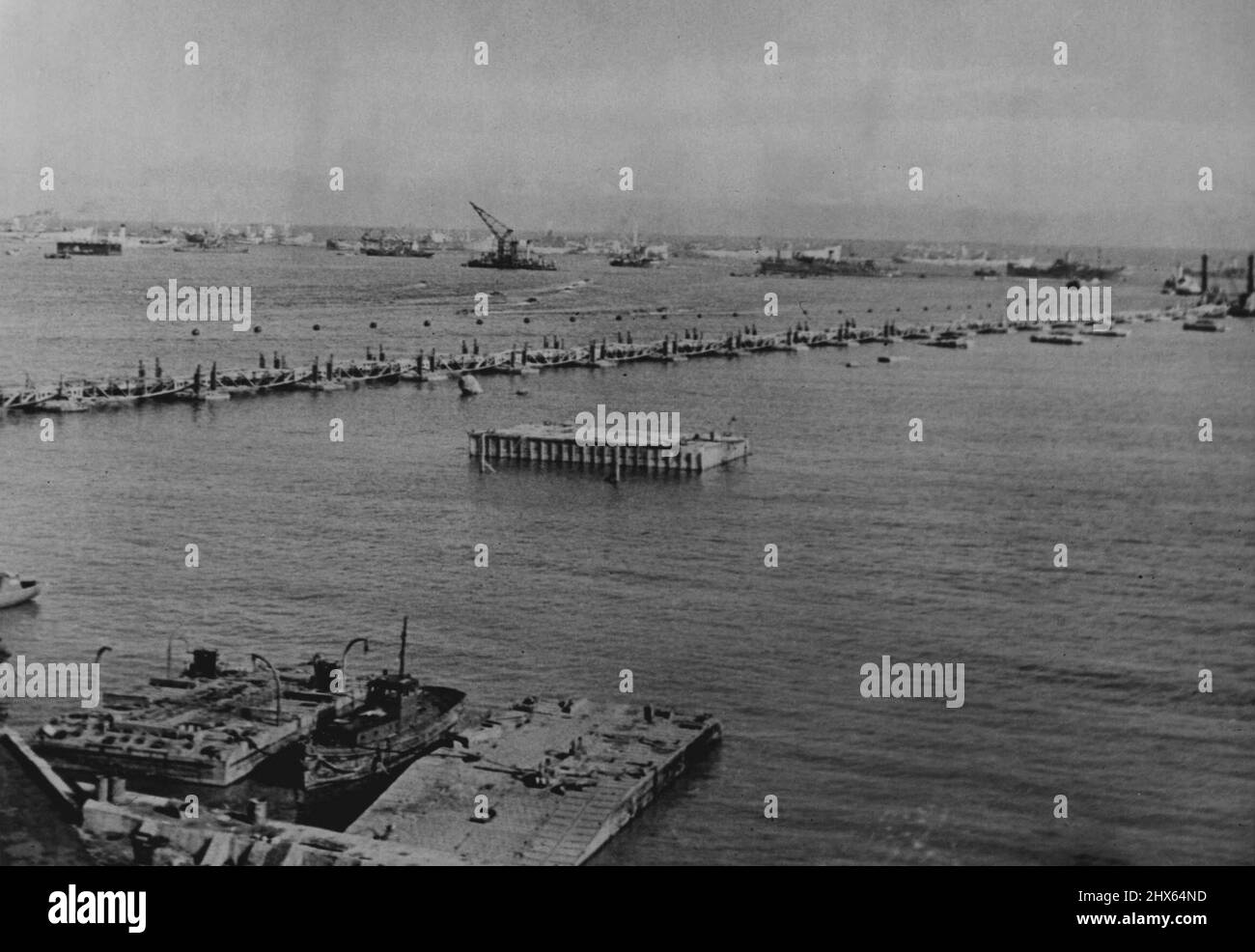 The Harbour We Towed Across To France - 'Bigger Than Dover Harbour' -- (left photograph) General view prefabricated port in position at Arromanches. Britain built a 'bigger-than-Dover harbour' at Arromanches on the Cherbourg Peninsula within twelve months of the tests with models. The harbour was working a week after D-day. With its help we landed two to three million men; thousands of lorries; millions of tons of equipment and supplies despite the worst June for forty years. January 15, 1945. ( Stock Photo