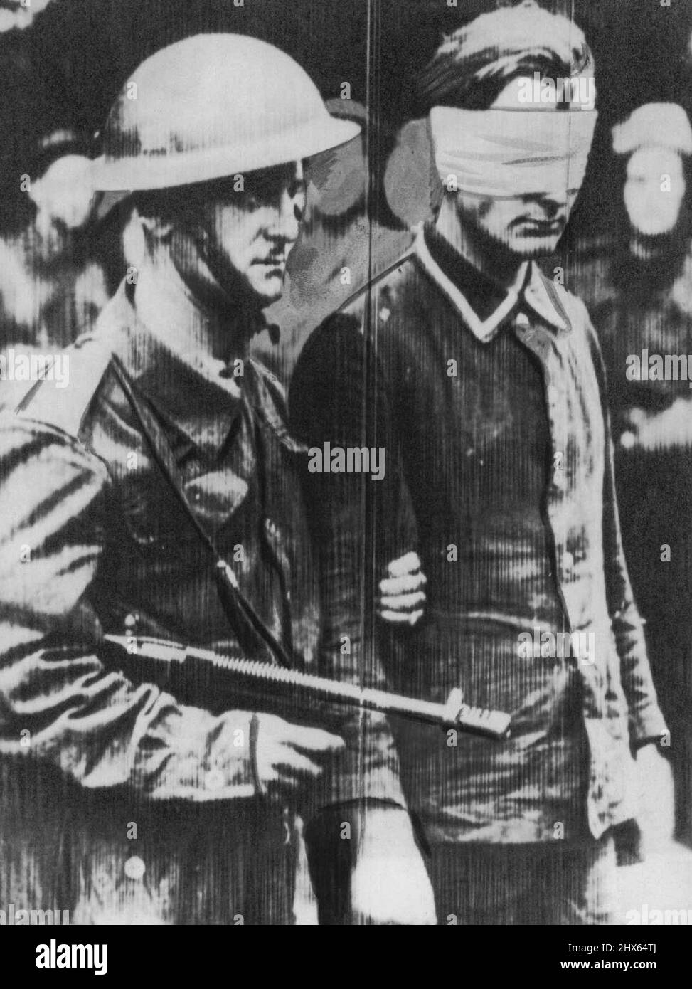 Commando Returns With Prisoner -- Back in Britain after the big Commando raid on Dieppe in German-occupied France, this stern Commando leads a blind-folded German prisoner. August 20, 1942 (Photo by AP Wirephoto). Stock Photo