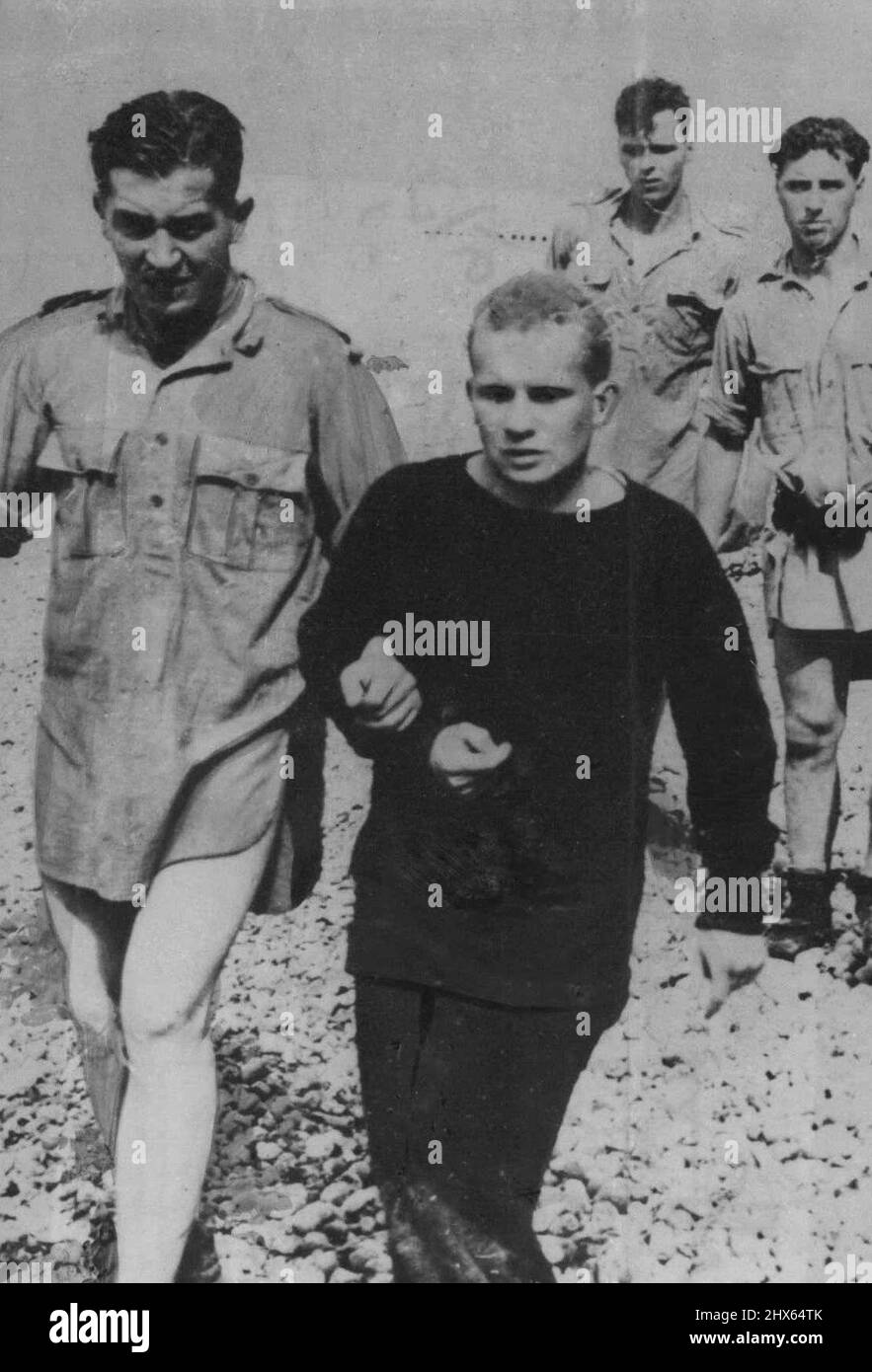 British Prisoners Captured at Dieppe Minus Trousers: New Picture Just Received. A new picture of the Dieppe 'Combined Operation', just received in London today, Sept. 9, showing British prisoners, captured during the raid, being Led, trouserless, up the Beach in charge of a German wearing a thick Jersey. September 9, 1942. (Photo by Associated Press Photo). Stock Photo