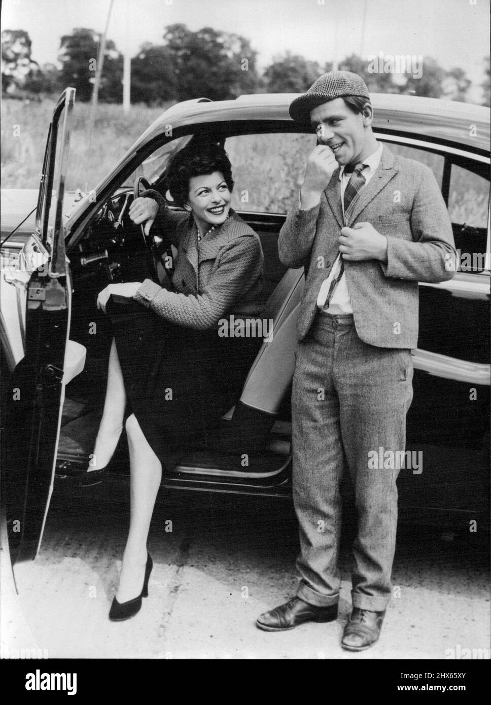 Going My Way? - Bashful little man requesting a lift from actress Joan Rice is comedian Norman Wisdom. They are pictured at Pinewood Studios, where they are filming together in 'One Good Turn', Norman Wisdom's second screen comedy. The film is being produced by Maurice Cowan and directed by John Paddy Carstairs - the team responsible for Wisdom's successful first film 'Trouble in store'. August 7, 1954. Stock Photo
