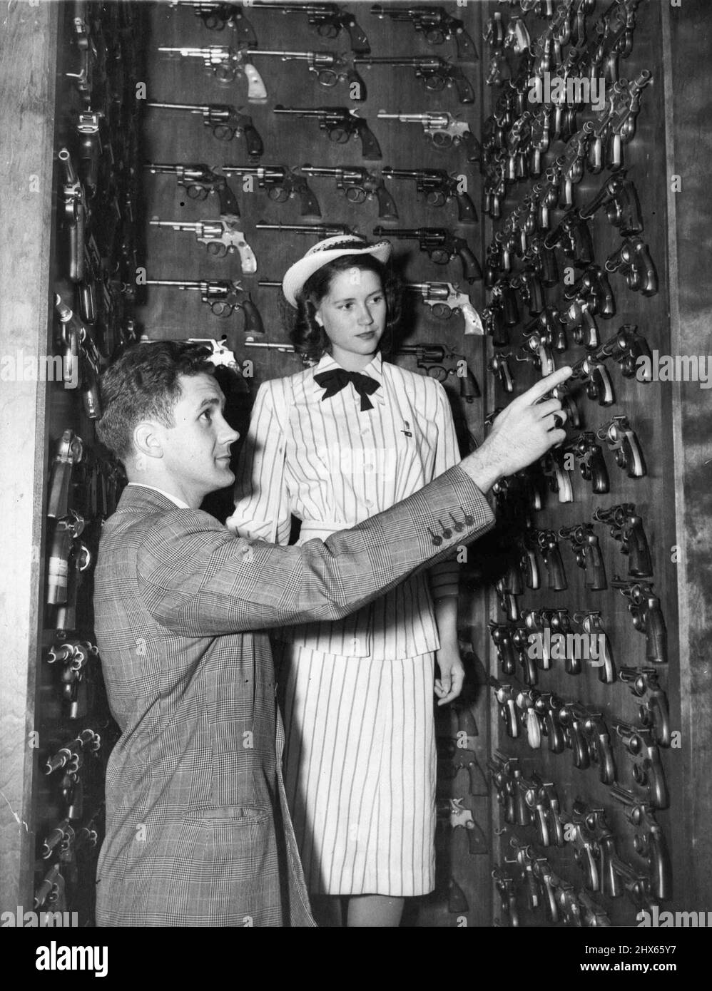 Pistol Library - George Ann Hicks of Edmond, Okla., President of American Legion 'Girl's Nation' views pistols in FBI headquarters' gun reference library. D.W. English, FBI special agent, explains them to her. August 25, 1947. (Photo by Wide World Photos). Stock Photo