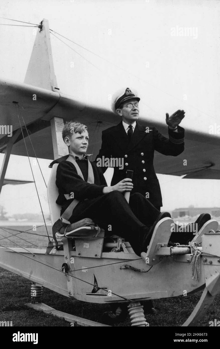 Budding Sailors Take To The Air. Lieutenant Commander J.S. Sproule, of Worthing, Sussex, the chief gliding instructor, briefs 16-year-old cadet A.B. Ducker, of Bristol, before being towed off by a lorry on his first flight. Away from their natural element, the sea, owing to the summer vacation, many cadets of Britain's famed Dartmouth Naval College (Devonshire) are now taking to air - spending a week of their holiday learning to glide at a Royal Naval Air Station near here. August 29, 1949. Stock Photo