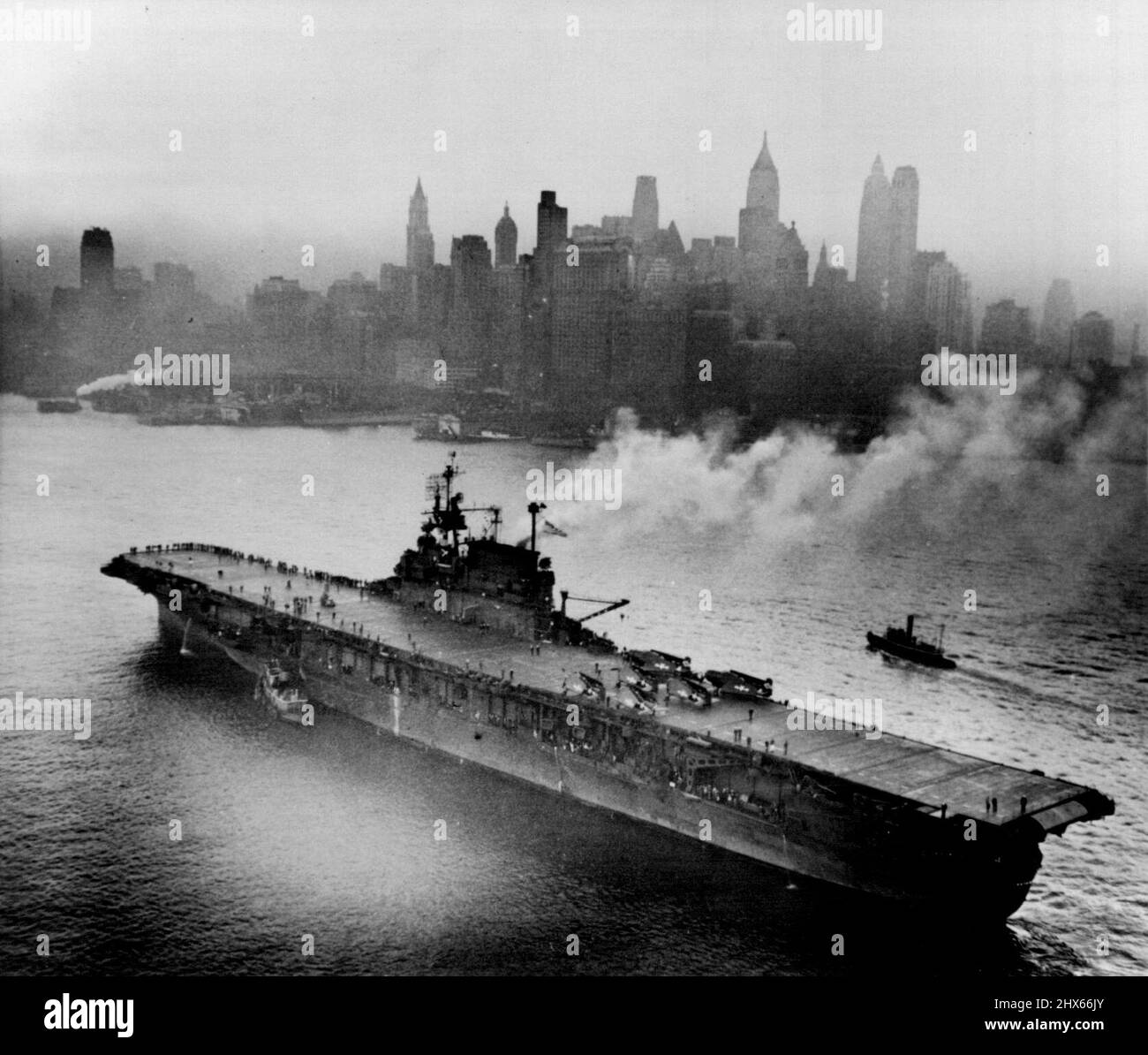 Flattop Meets Skyscrapers -- Veteran of the Pacific carrier USS enterprise steams up the river past New York's downtown skyscrap as it arrives in the big city. It was first Major Pacific fleet ship to ***** preparatory to Navy Day (Oct.27th). October 17, 1945. (Photo by ACME). Stock Photo