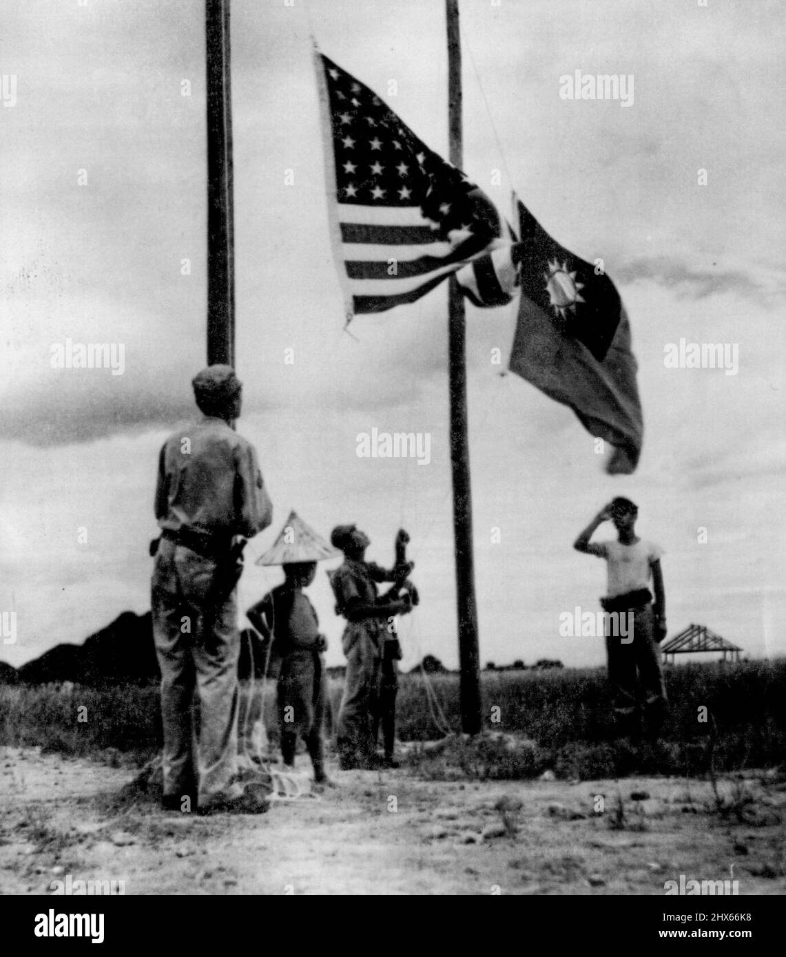 Old Glory And Chinese Flag Go Up -- The stars and stripes and the Chinese flag are raised over the area near Luichow after its evacuation by the Japanese. The ***** saluting was not identified. July 27, 1945. (Photo by Associated Press Photo). Stock Photo