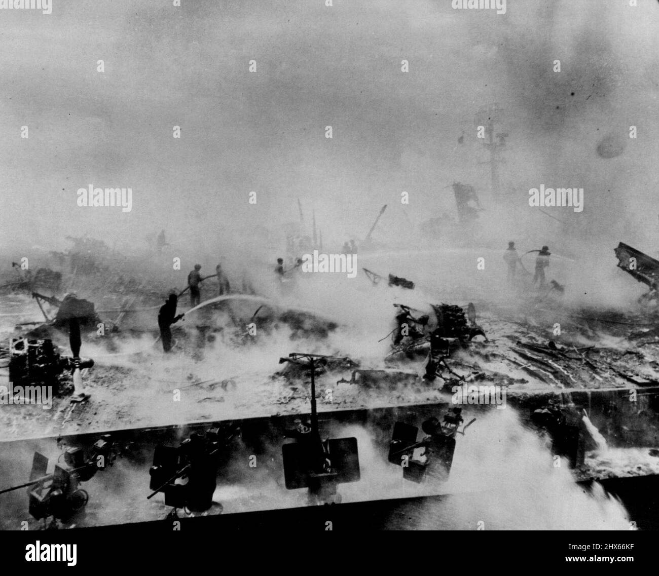 Crew of the bunker hill fights courageously to bring flaming gasoline on her flight deck under control. Charred wreckage of planes which were awaiting take-off at the time of the attacks attests to the destruction the stricken carrier suffered. June 21, 1945. (Photo by ACME). Stock Photo