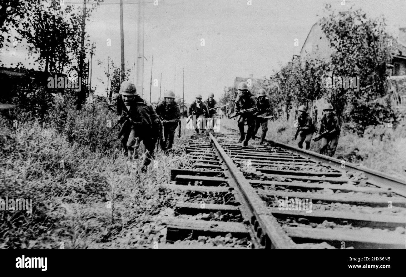 Chinese Troops Are Their Quarry -- With their grim faces set, and fixed-bayonet rifles at the ready, these Japanese Marines wearing their steel helmets charge along a railway track outside Shanghai, in pursuit of fleeing Chinese soldiers. December 7, 1937. Stock Photo