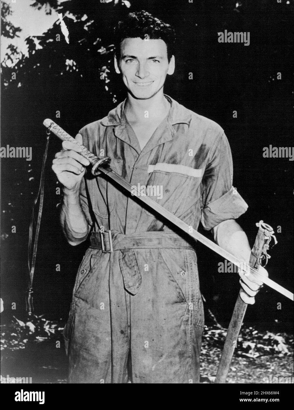 Trophy Taken From A Fallen Japanese Officer -- A corporal of the U.S. Army Air Forces displays a Japanese sword and scabbard taken from a dead enemy officer in the fighting on Guadalcanal in the Solomon Islands. February 8, 1943. (Photo by Interphoto News Pictures, Inc.). Stock Photo
