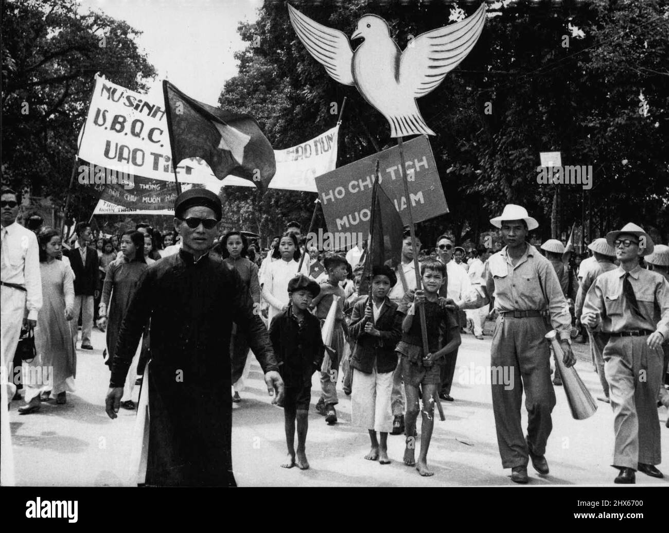 Vietnam March Into Hanoi -- Children with white peace Doves and slogans follow troops into Hanoi. More than 5,000 Vietminh staged a victory parade in Hanoi October 9. As they took over the city under the terms of the Geneva agreement. Cheering flag-waving civilians thronged the streets as the troops arrived. October 18, 1954. (Photo by Associated Press Photo). Stock Photo