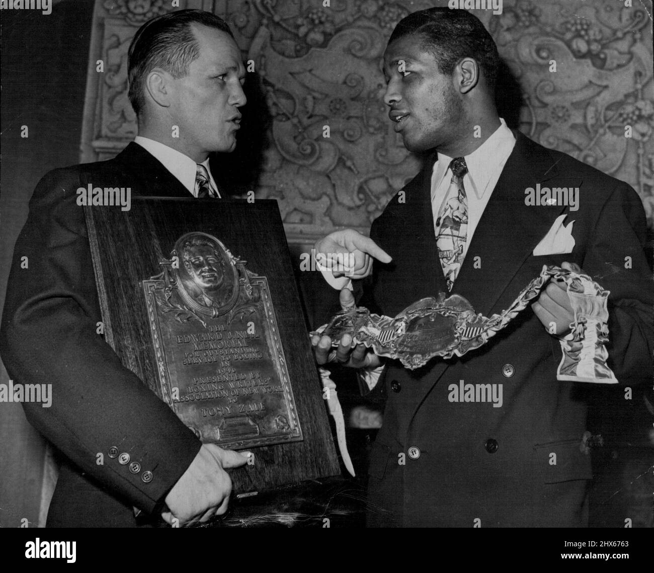 Receive Awards From Boxing Writers -- Tony Zale (left), middle weight boxing champion, holds the Edward J. Neil Plaque and Ray (Sugar) Robinson. welterweight champ, holds a belt Awarded Jan.22 at the annual dinner of the Boxing writers Association of New York city. The Neil award was made in memory of Edward J. Neil, Associated Press boxing writer and war correspondent, killed in the Spanish revolution. The belt held by Robinson was awarded by Ring Magazine. January 22, 1947. (Photo by Associate Stock Photo
