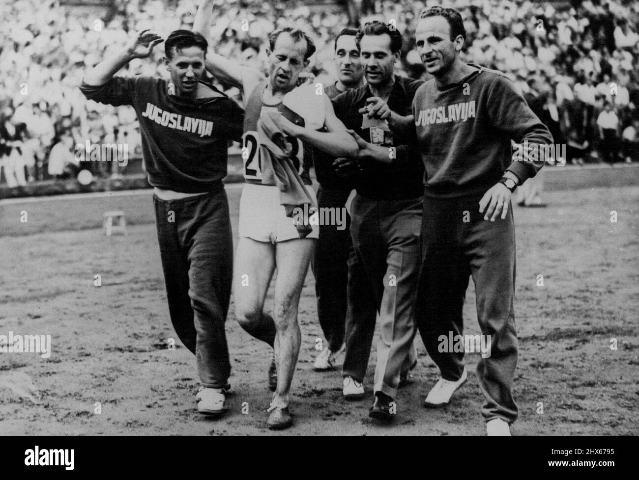 The XIVth Olympiad - Czech Wins The 10,000 Metres -- E. Zatopek (Czechoslovakia) after he had won the 10,000 metres at Wembley Stadium, being assisted off the track by members of the Yugoslav team. October 8, 1948. (Photo by Sport & General Press Agency, Limited). Stock Photo
