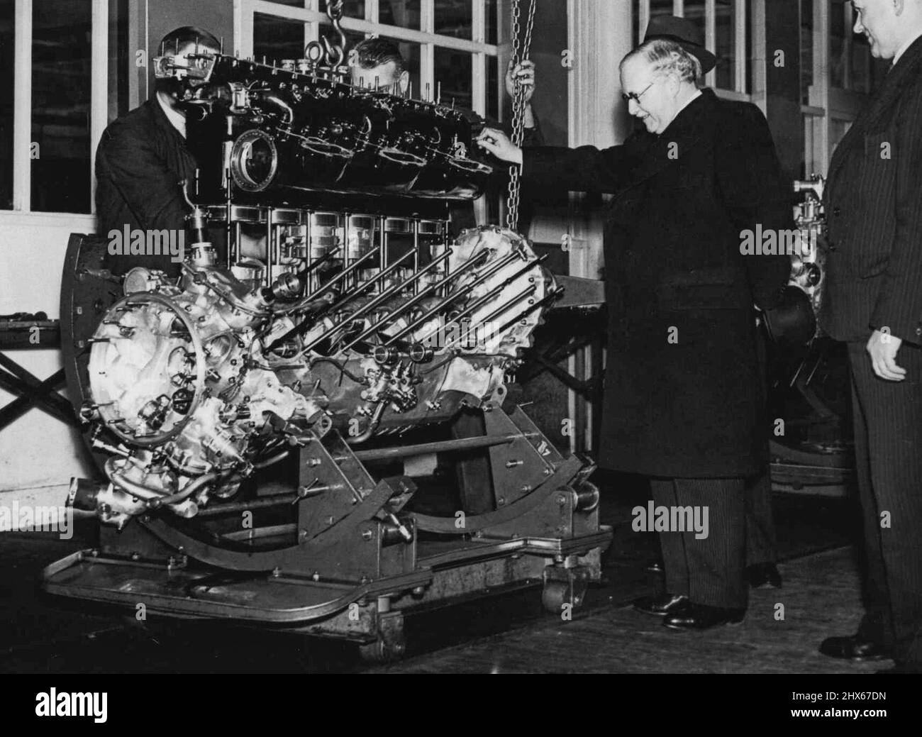 Air Minister Visits Aero Engine Works -- Sir Kingsley Wood watching the assembly of aero engines during his visit to the Rolls-Royce works yesterday. Sir Kingsley Wood, the Air Minister, yesterday paid a visit to the Rolls-Royce aero engine works at Derby. October 12, 1938. (Photo by Topical Press). Stock Photo