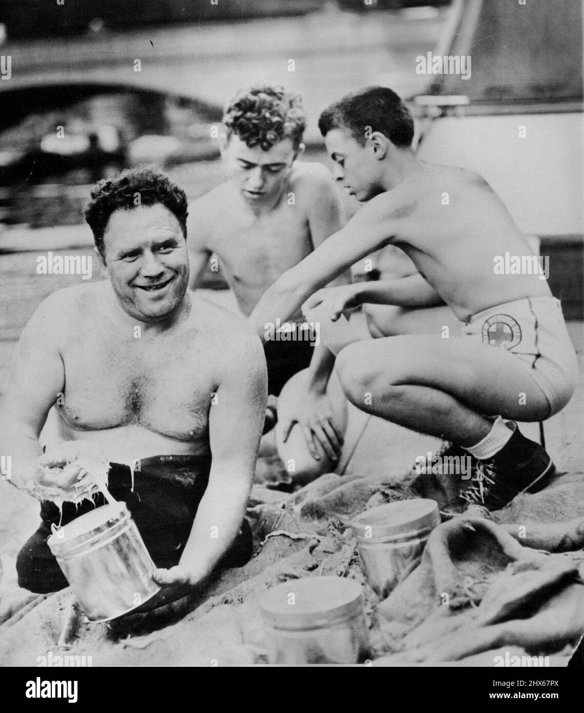 Legless Swimmer Prepares For Non-Stop -- Charles Zimmy, legless swimmer, is shown at Albany, N.Y., August 24, as he prepared to apply grease to his body for his attempt to swim non-stop from Albany to New York City down the Hudson River. Helping him, center and right, are Robert Sackrider and Roy Jones, members of the Albany Y.M.C.A. August 24, 1937. (Photo by Associated Press Photo). Stock Photo