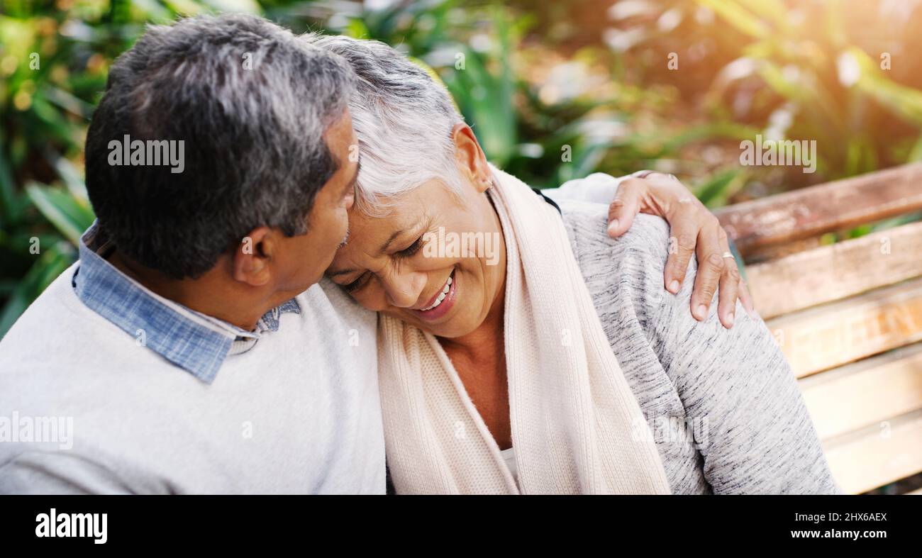 Real love withstands the test of time. Shot of an affectionate senior couple sitting down on a bench together and relaxing at the park. Stock Photo