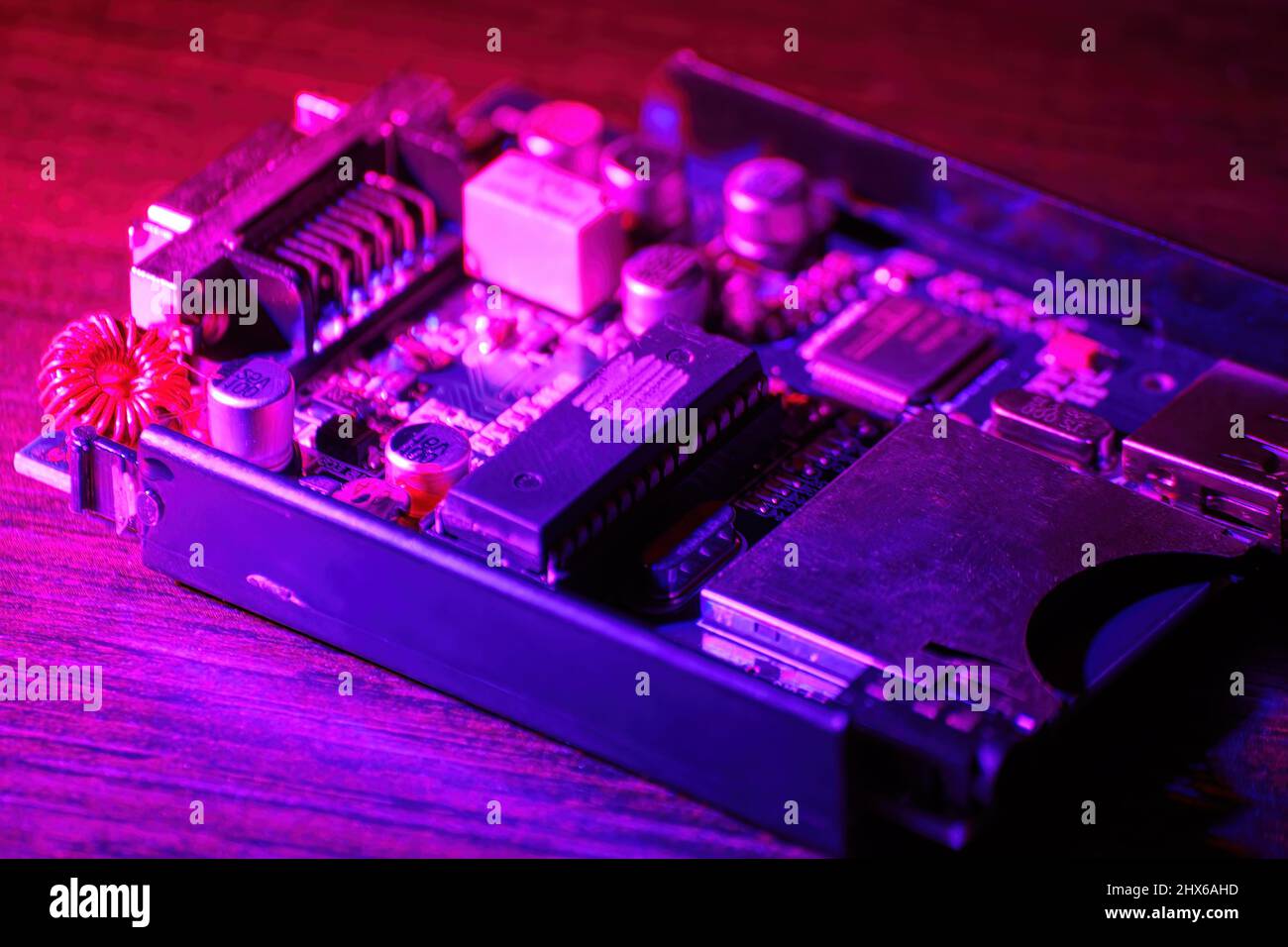 Small PCB and microcircuit computer on the table in the purple neon lights. Abstract technologies and IT backgrounds Stock Photo