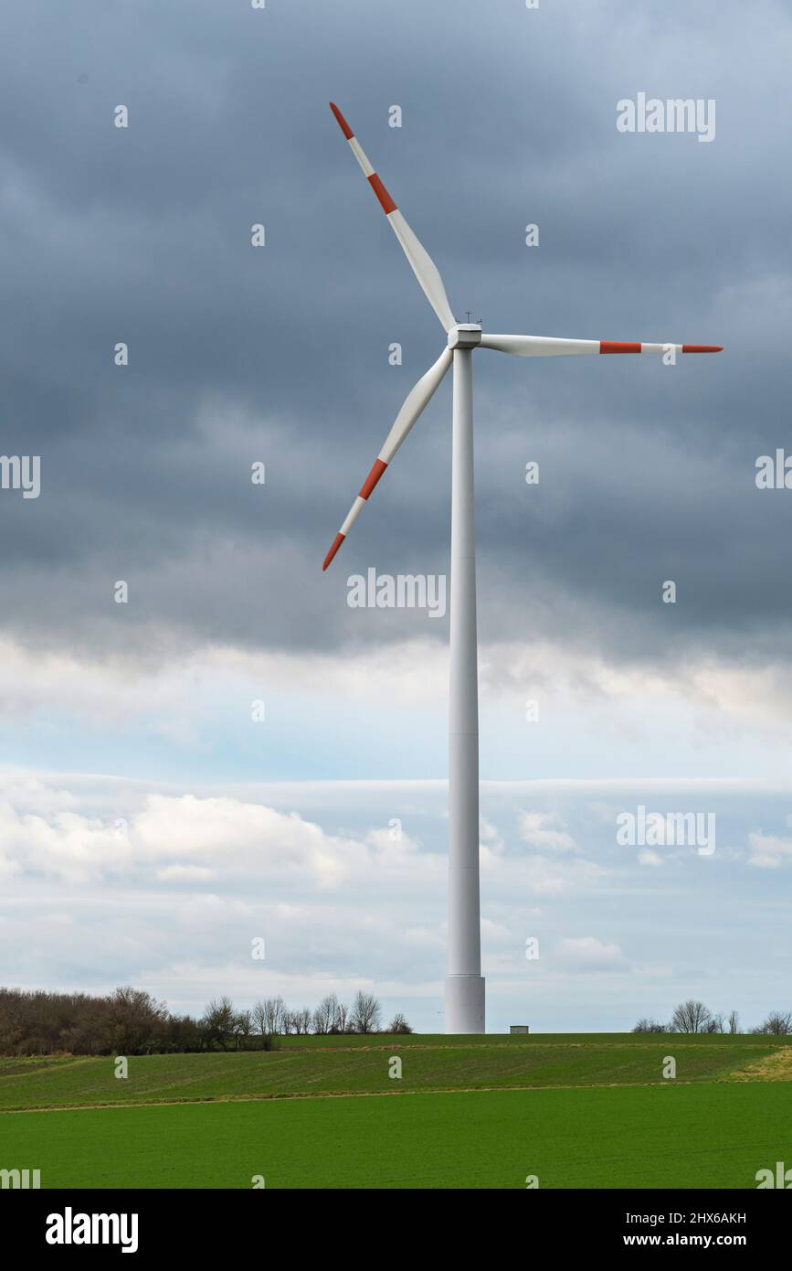 Wind turbine against a cloudy sky in a green agricultural landscape, a ...