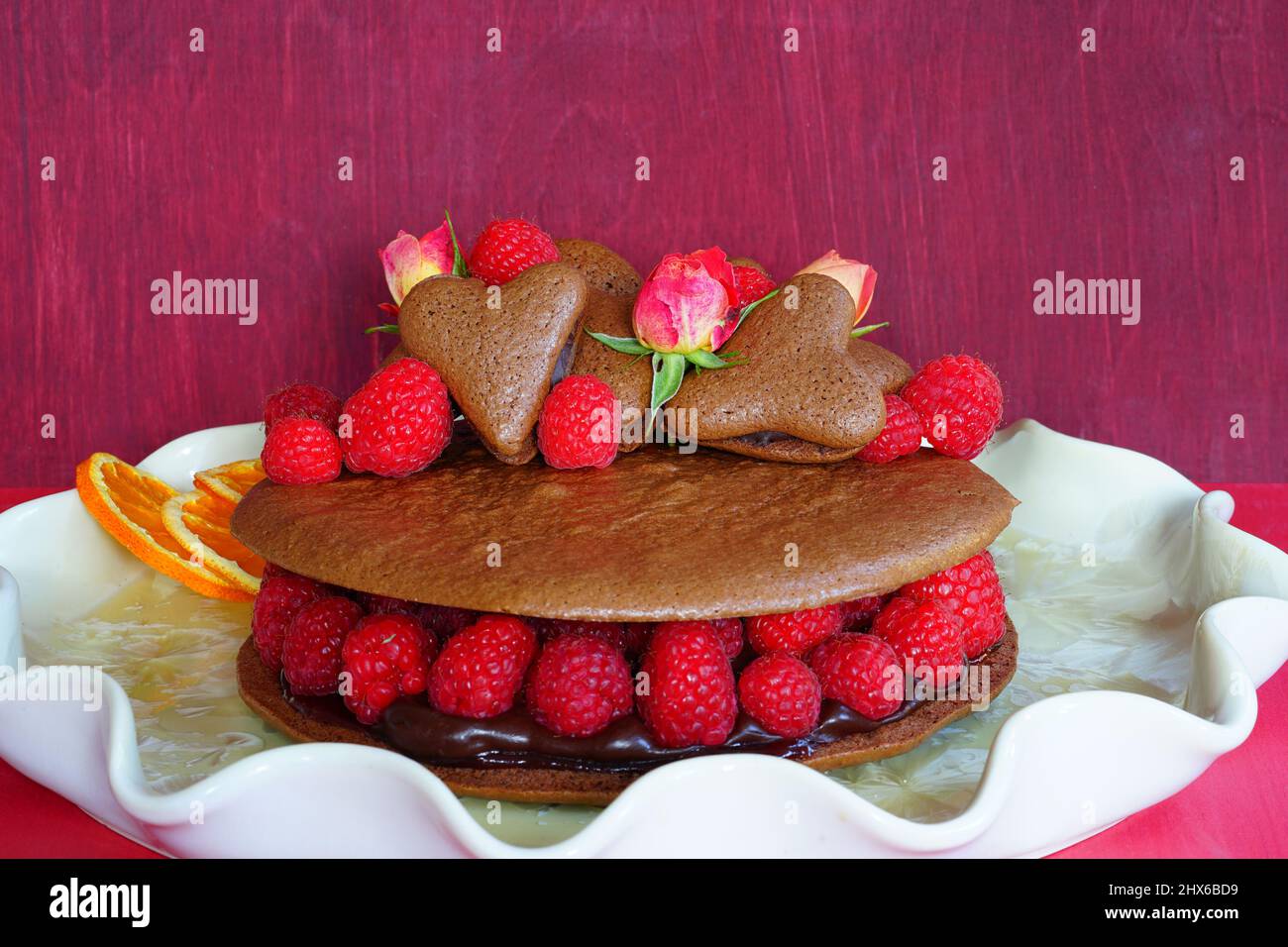 A giant chocolate macaron cake with fresh raspberries and rose flowers Stock Photo