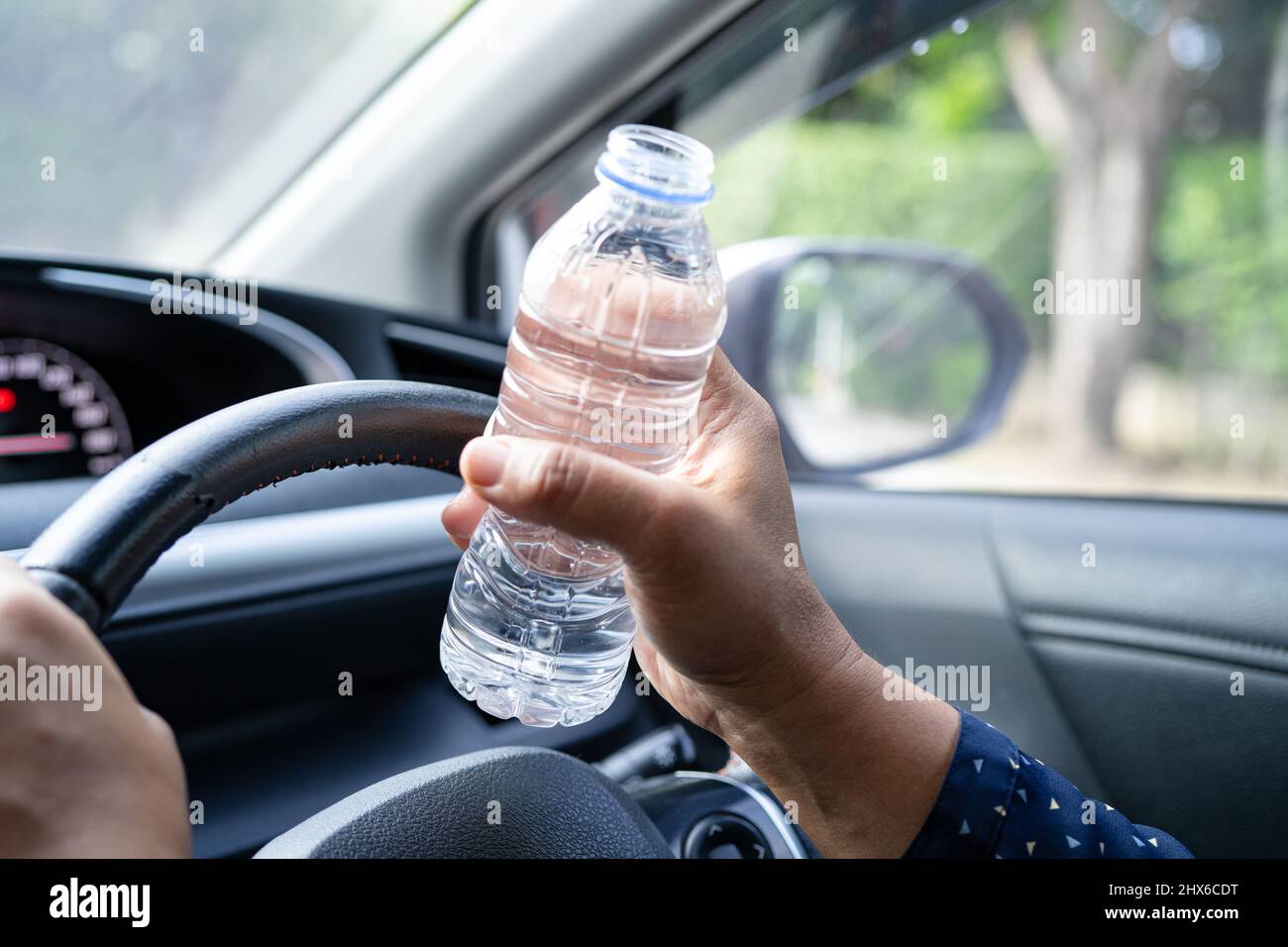 Asian woman driver holding bottle for drink water while driving a car.  Plastic hot water bottle cause fire Stock Photo - Alamy