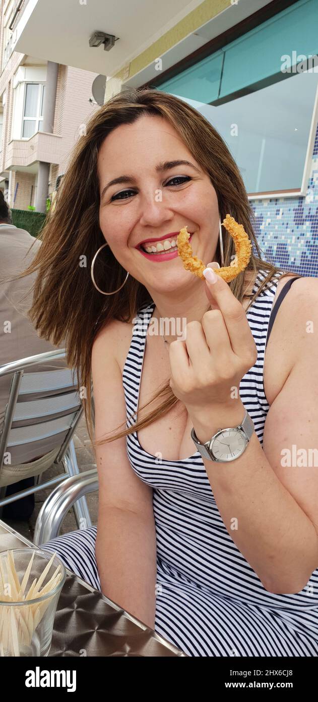 beautiful woman eating battered squid on a terrace Stock Photo