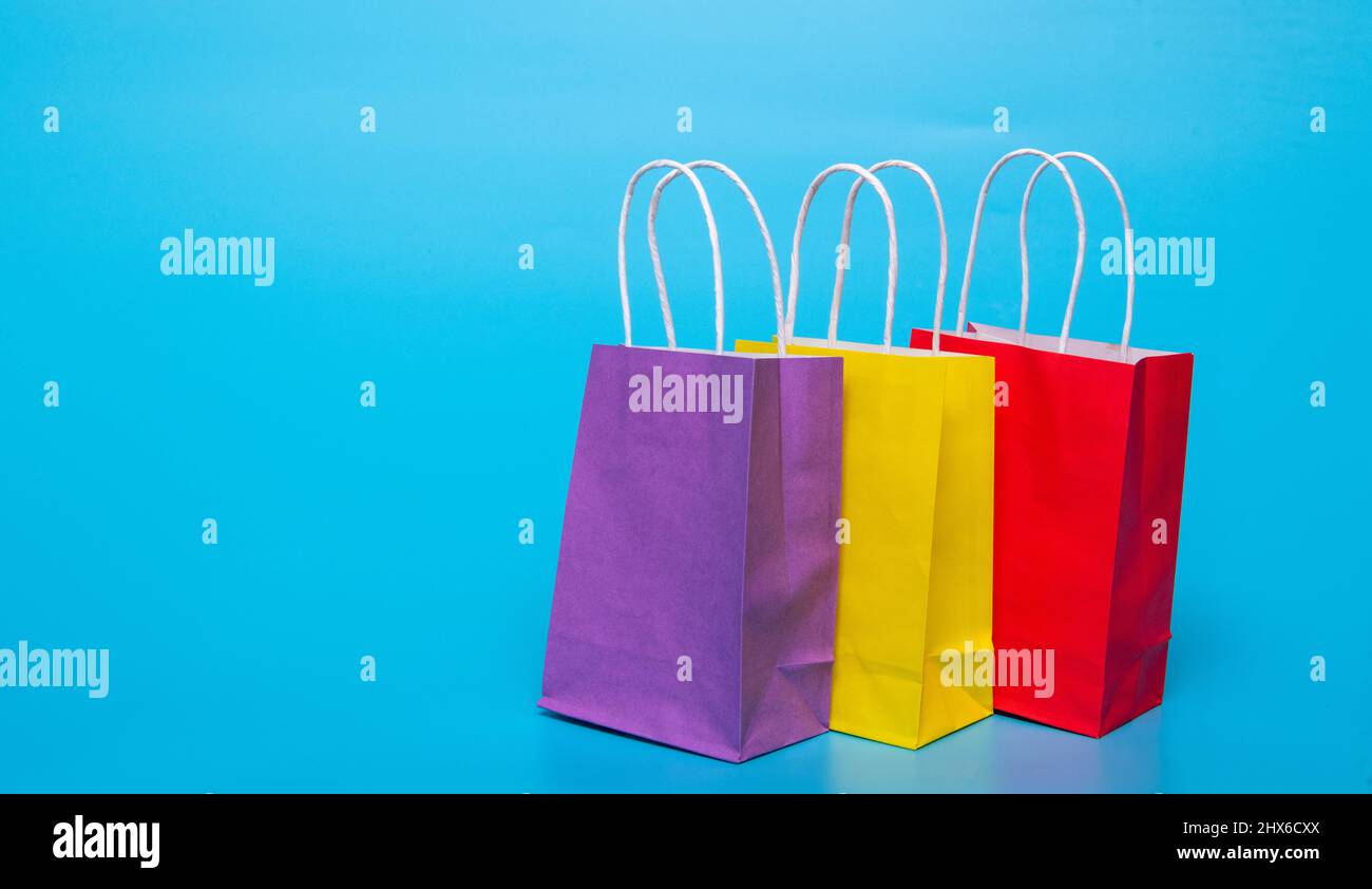three colored paper bags on a blue background Stock Photo