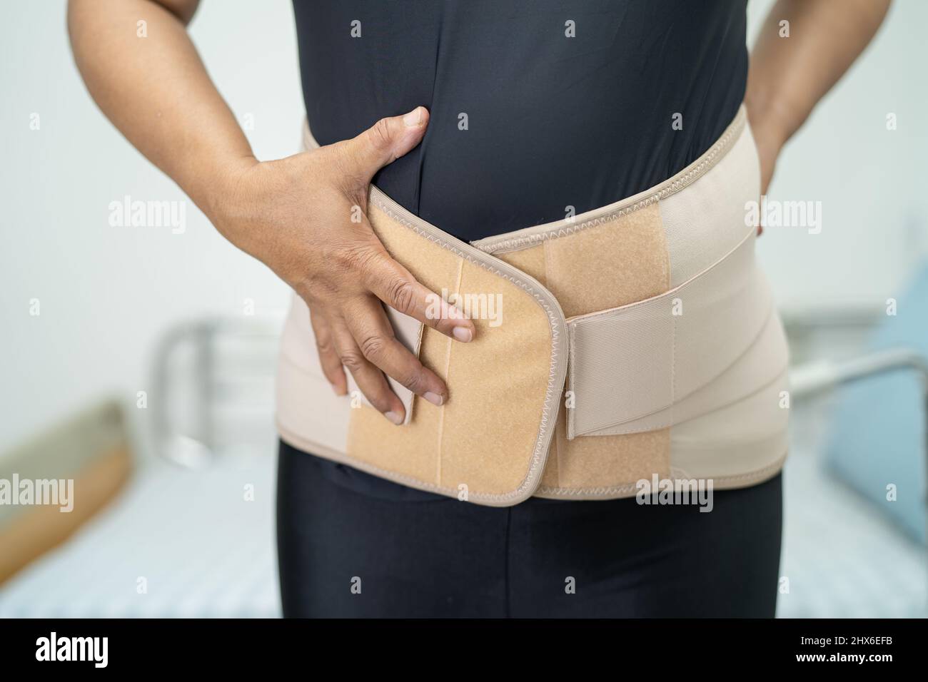 Asian lady patient wearing back pain support belt for orthopedic lumbar ...