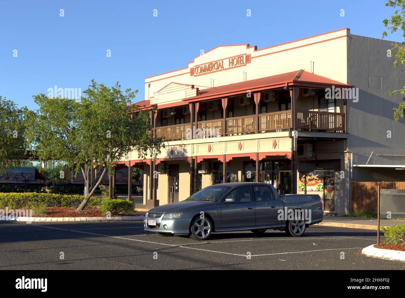 Commercial Hotel (1938) Clermont Queensland Australia Sunlit view of a rustic two-story hotel facade with balcony and parked ute on a clear day Stock Photo