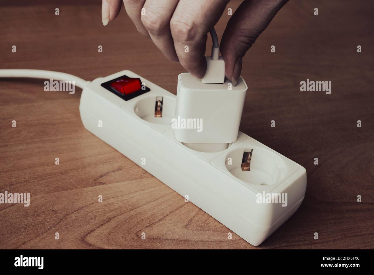 Female hand plugging usb cable into phone charger adapter Stock Photo