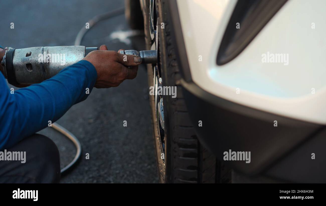 mechanic man using an electric drill to loosen the bolts of vehicle