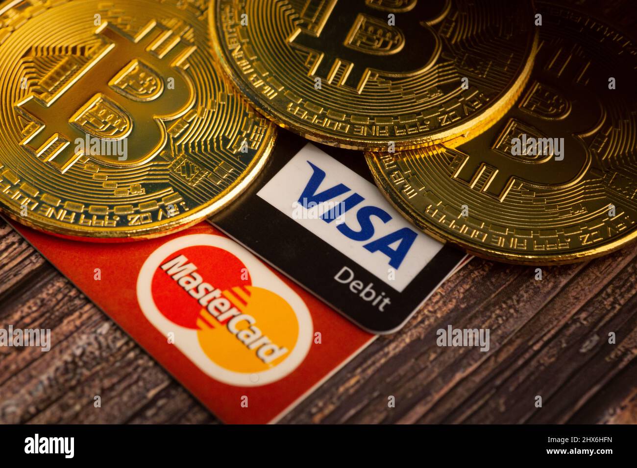 Bayan Lepas, Penang, Malaysia - January 2 2022: Golden Bitcoin with Visa and Mastercard logo token on a wooden background. Digital currency. Stock Photo