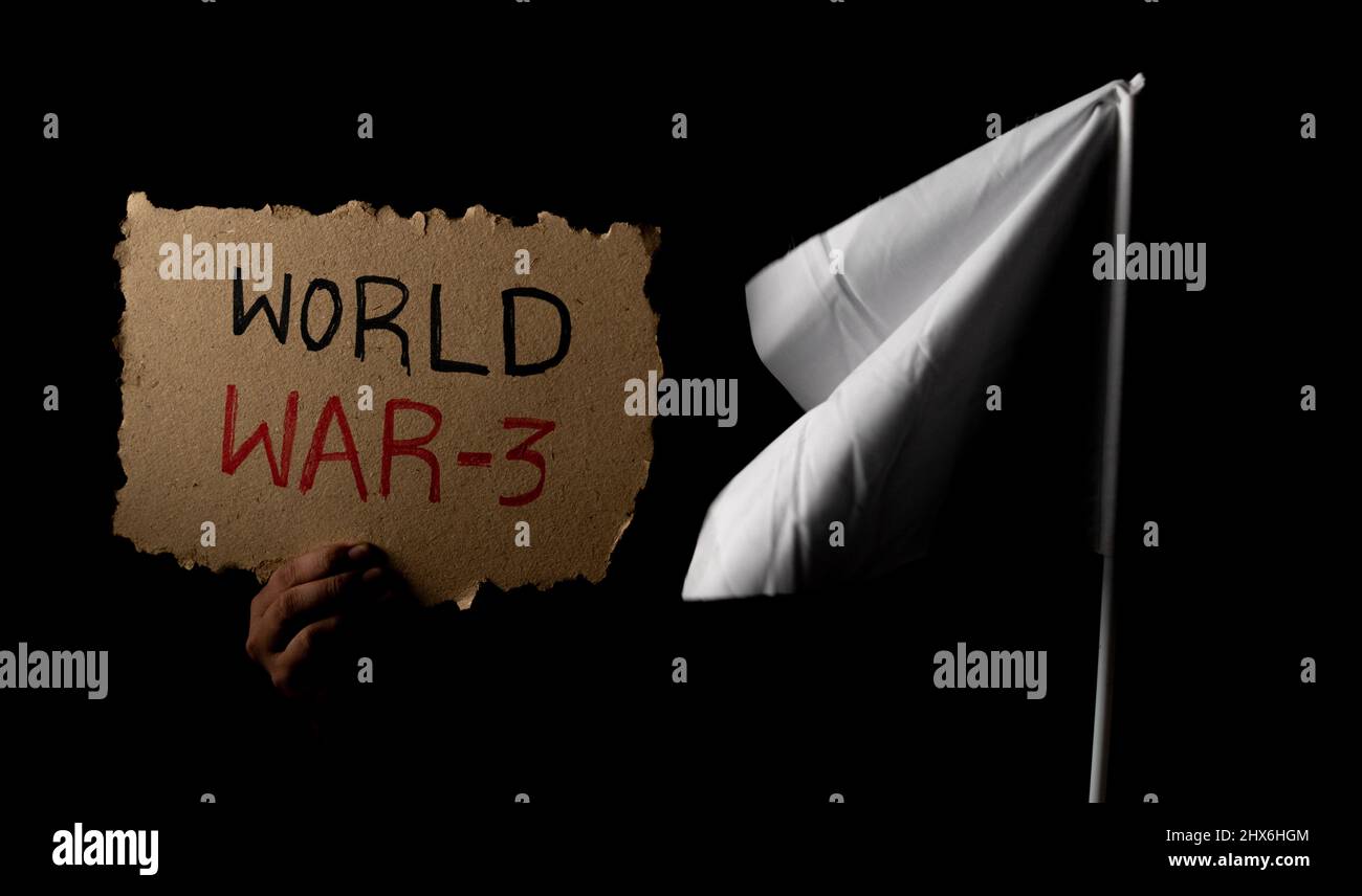 Close up of hands holding world war 3 sign board with white flag in dark background - concept of peace, stop crisis or conflict and demonstrations Stock Photo
