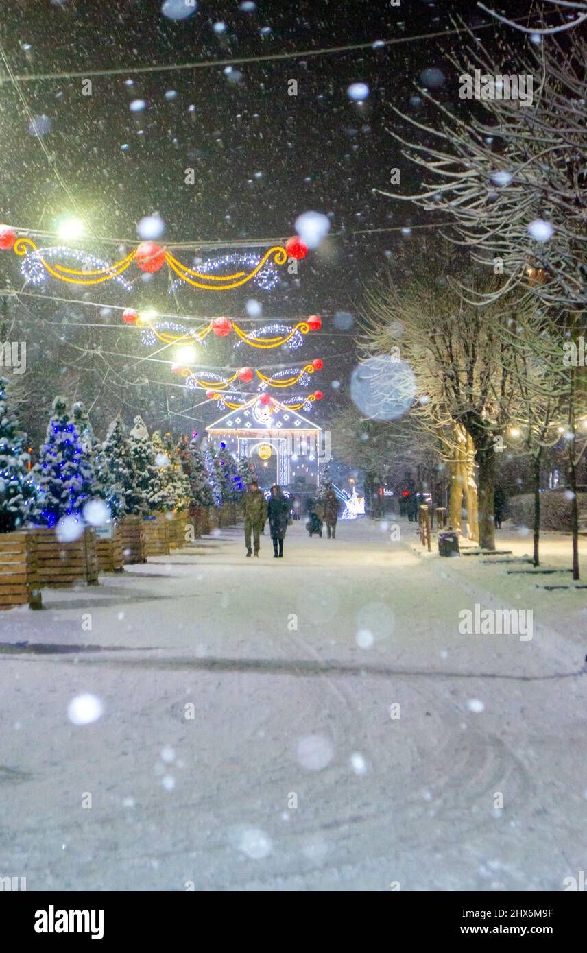 City street during snowfall at winter night. Beautiful illumination Stock Photo
