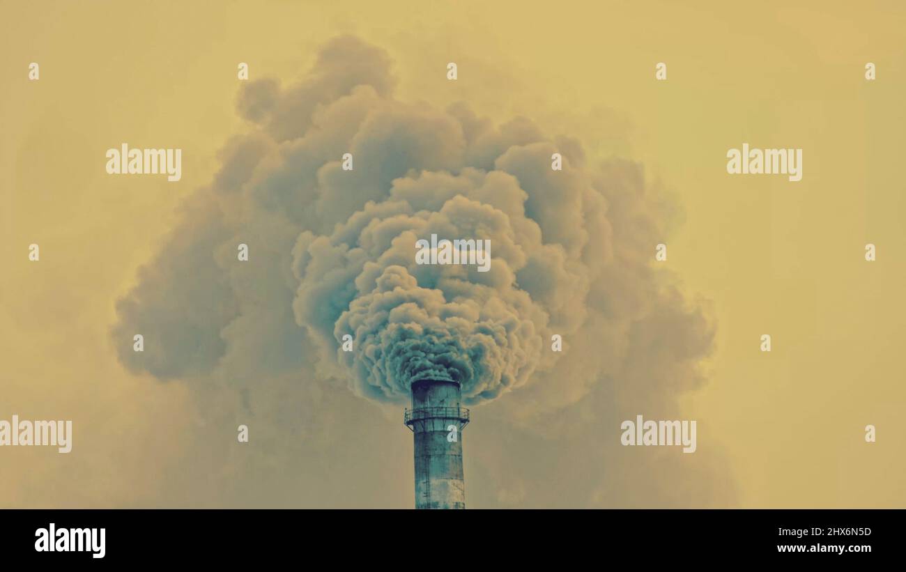 This smoke coming from the chimney in a factory. Harmful emissions into the atmosphere, from the pipe. Serious damage the environment. Plant stack Coaling station. Close up shot. Dark sad view. Stock Photo