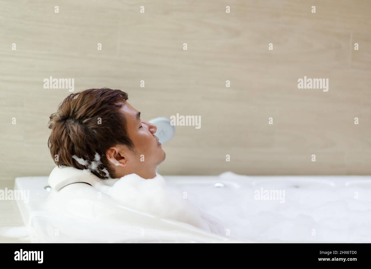 young man relaxing in bathtube with eyes closed in bathroom Stock Photo
