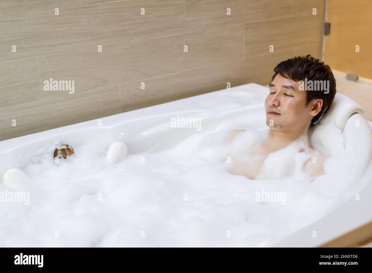 young man relaxing in bathtube with eyes closed in bathroom Stock Photo