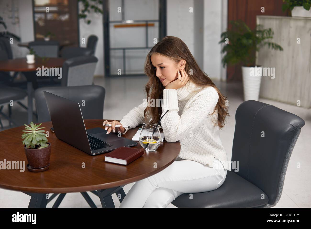 Young woman working on laptop while sitting in cafe Stock Photo