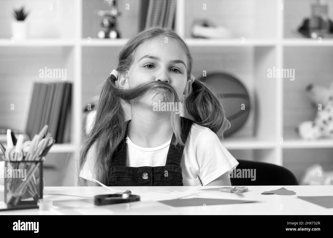 funny child having fun with long hair pony tail at school lesson in classroom wear uniform, fun Stock Photo