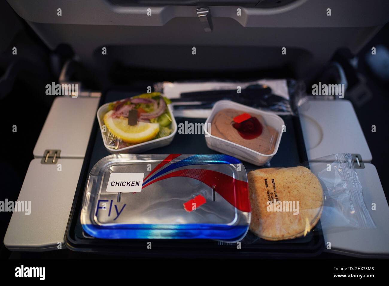 A chicken airline meal is placed on a passenger's tray, in the cabin of a British Airways Airbus