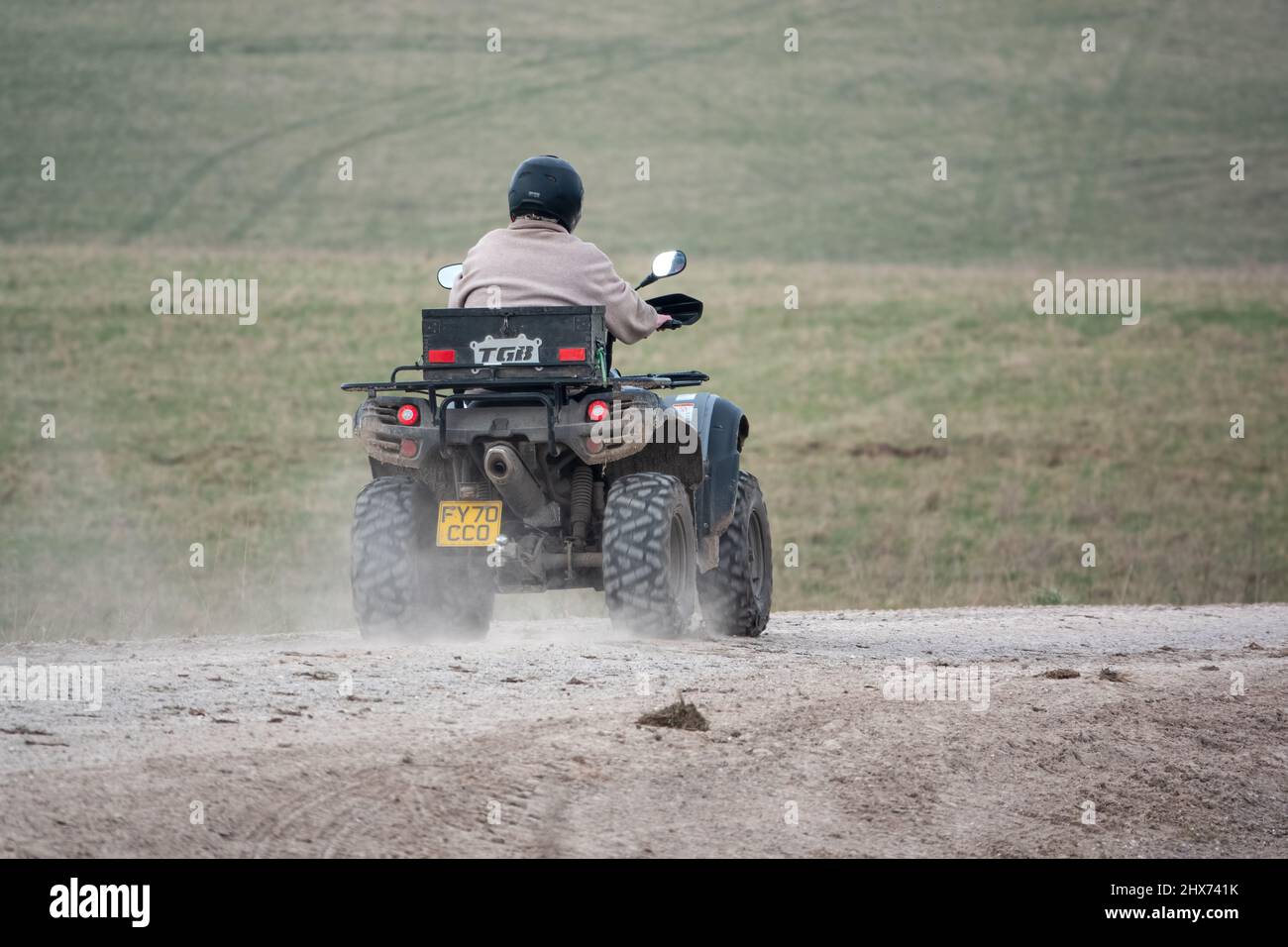 a quad biker with lights on riding his offroad quad bike along a stone
