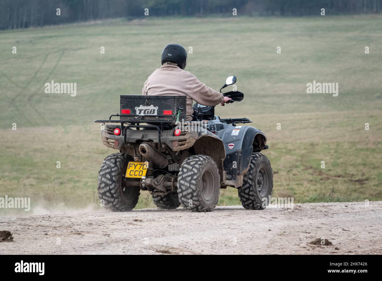 a quad biker with lights on riding his offroad quad bike along a stone