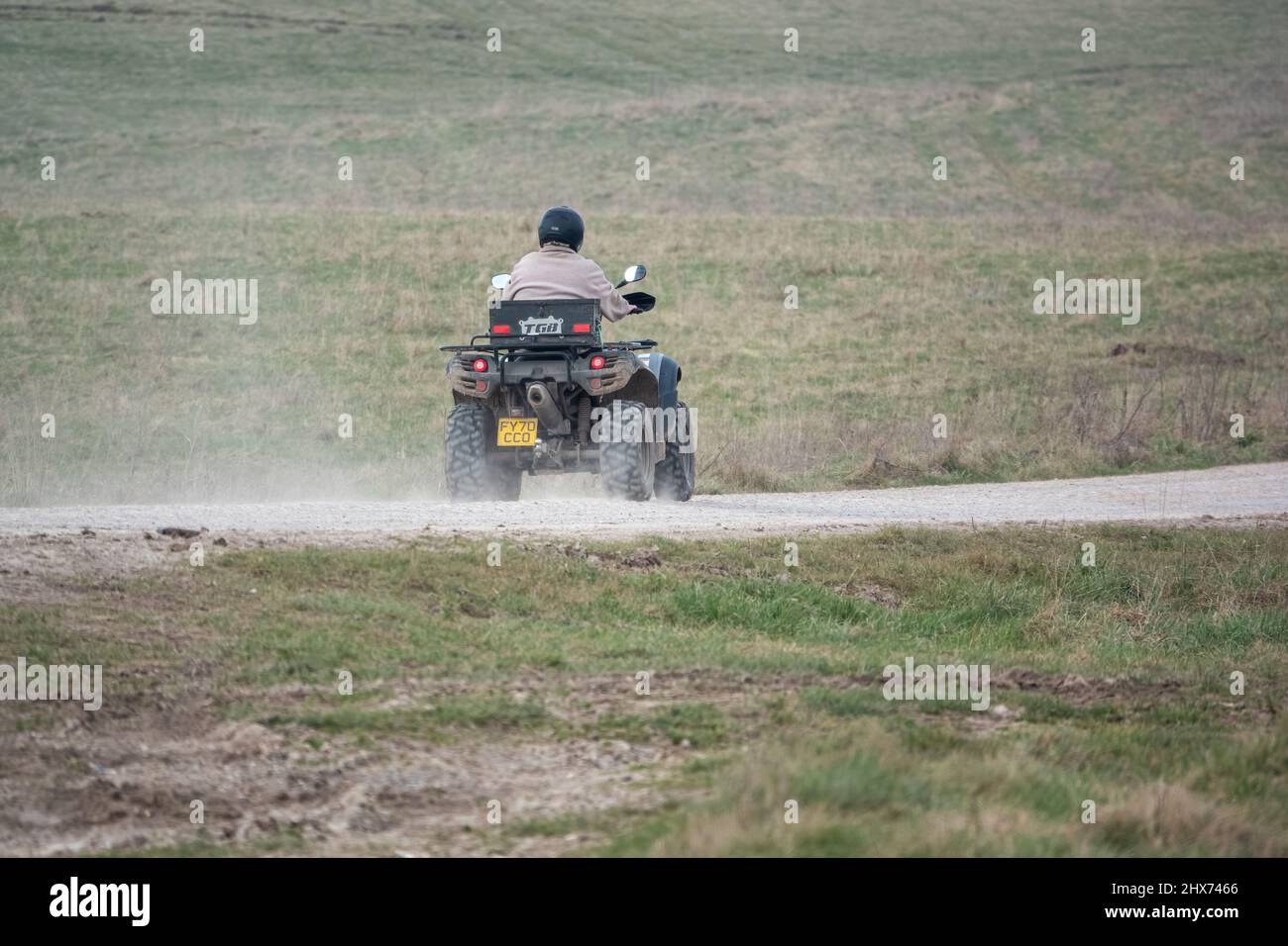 a quad biker with lights on riding his offroad quad bike along a stone