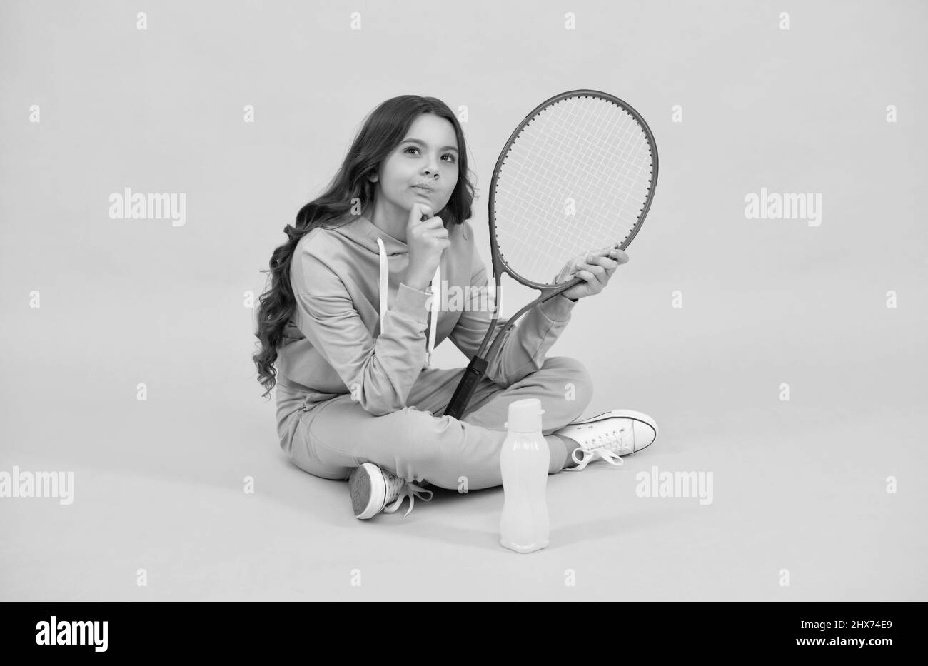 thinking child with tennis racquet. teen girl after sport training. dedicated to fitness. Stock Photo