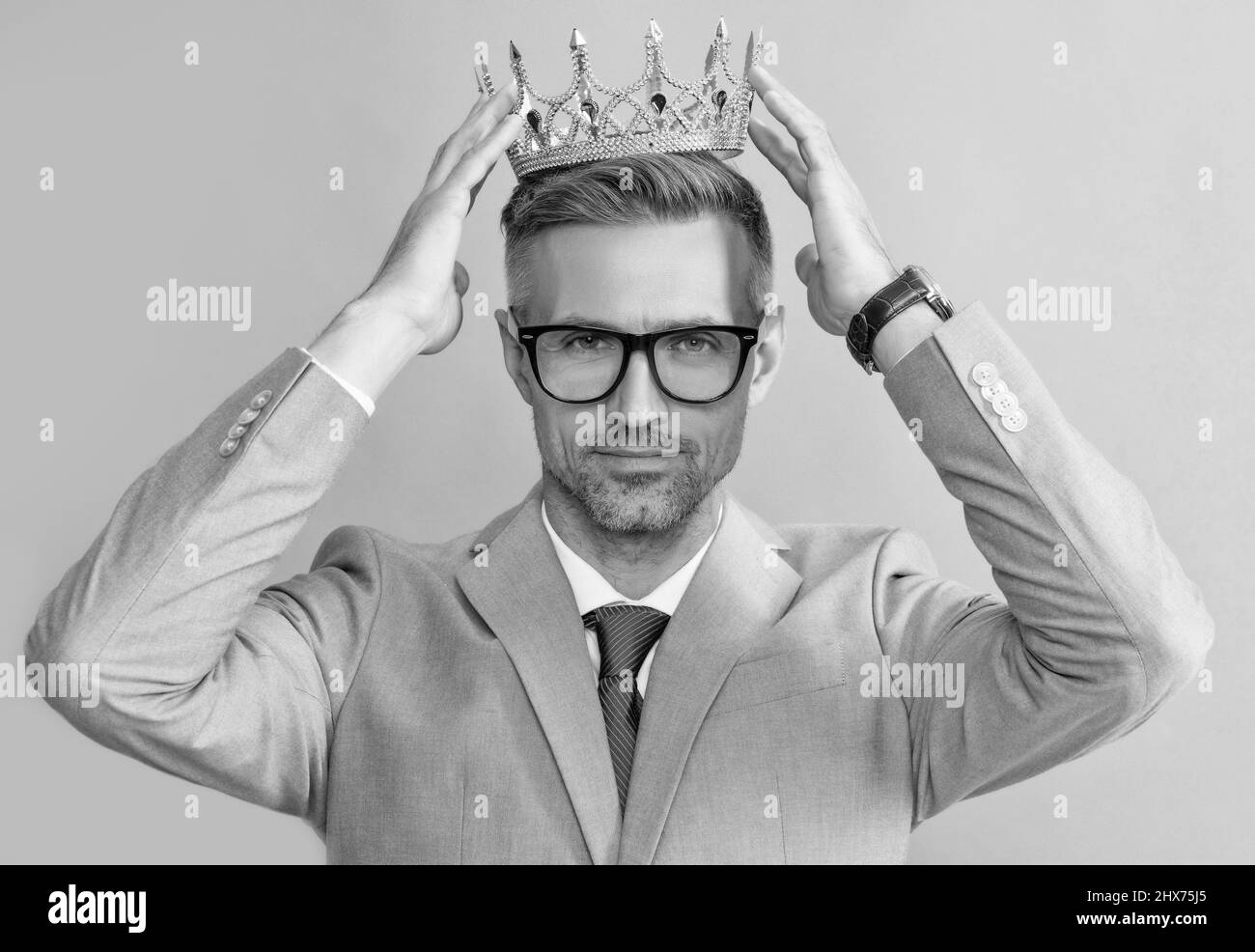 grizzled guy wearing king crown on grey background, success Stock Photo