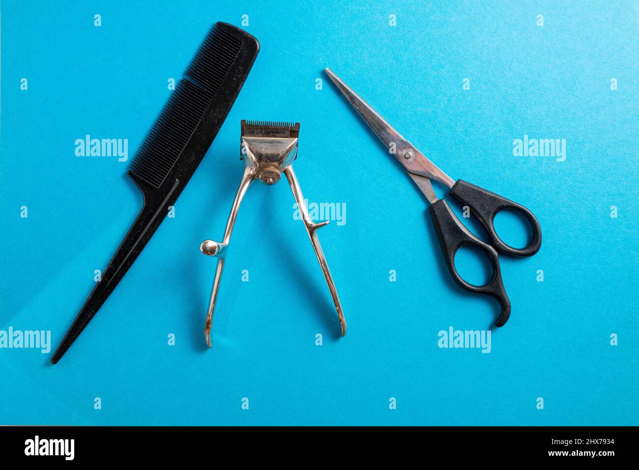 old hair clippers on a blue background with scissors and comb ,top view , copy space Stock Photo