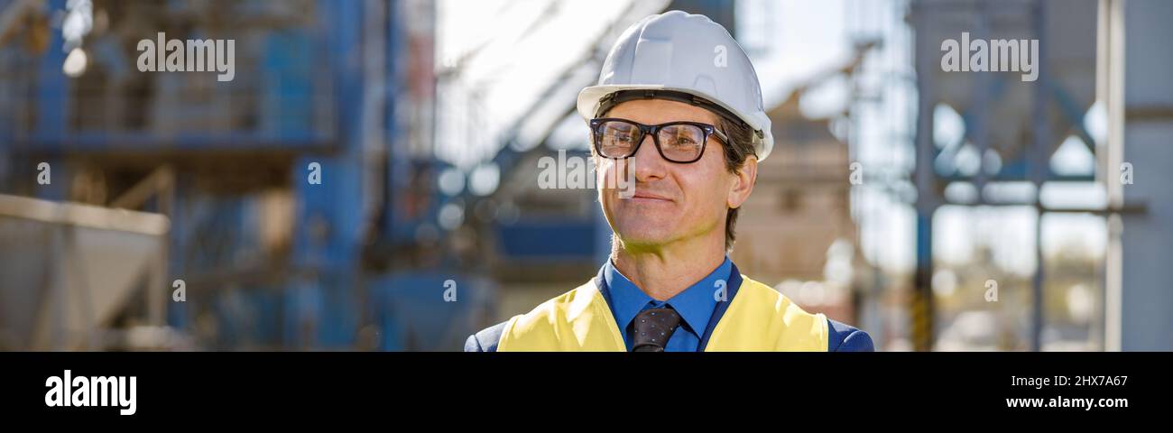 Joyful man engineer standing outdoors at factory Stock Photo