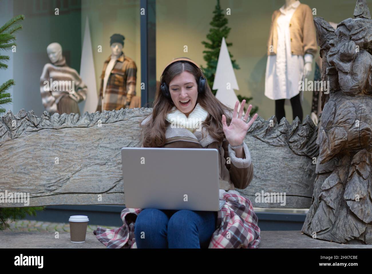 A young woman talking to someone via laptop and waving hi Stock Photo